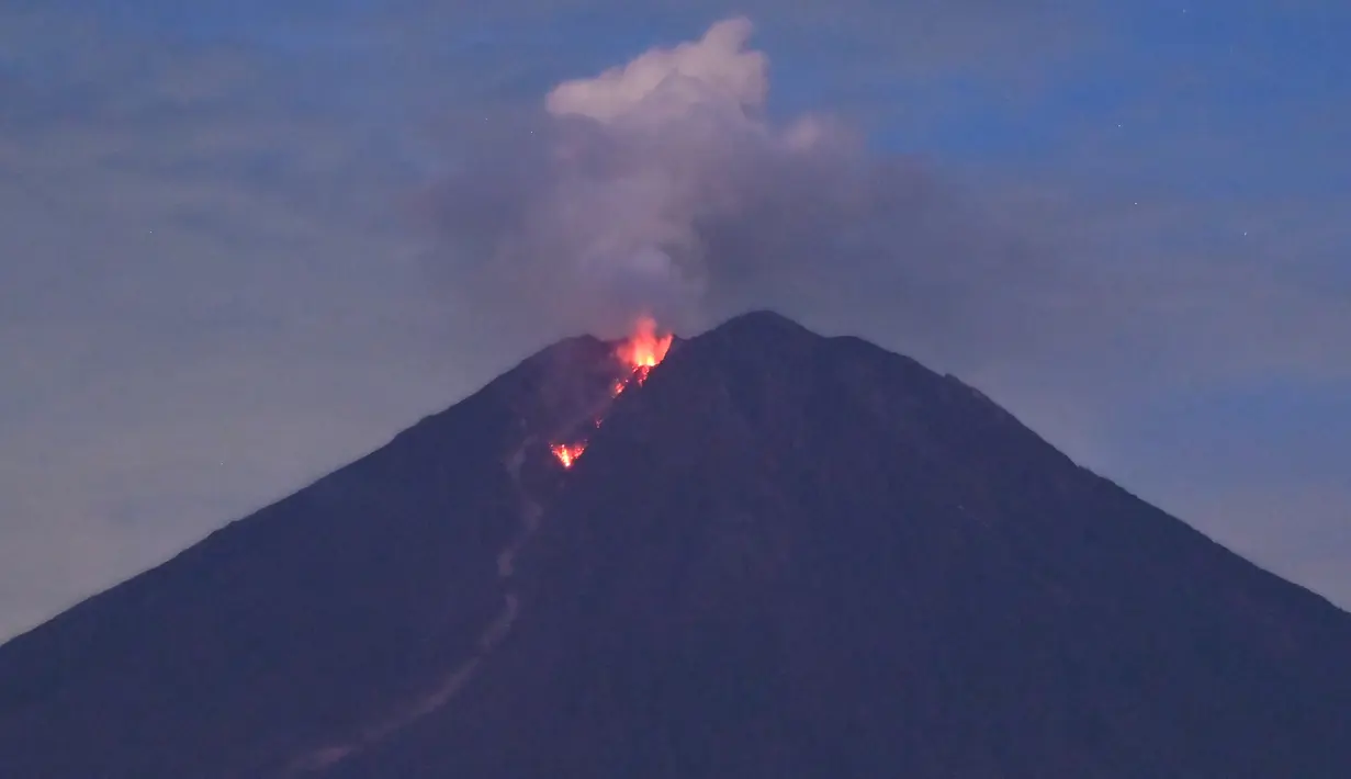 Gunung Semeru mengeluarkan lahar panas yang terlihat dari desa Curah Kobokan di Lumajang, Jawa Timur, Rabu (8/12/2021).  Masyarakat/pengunjung/wisatawan diimbau untuk tidak beraktivitas dalam radius 1 Km dari kawah atau puncak Gunung Semeru. (ADEK BERRY / AFP)