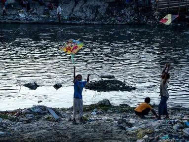 Anak laki-laki menerbangkan layang-layang di tepi sungai menjelang festival Hindu Dashain di Kathmandu (7/10/2020). Festival ini yang paling dinantikan di Nepal, Bhutan, Burma, dan perbukitan India Utara. (AFP/Prakash Mathema)