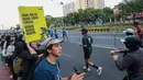 Seorang penonton membawa poster bertema kebakaran hutan dan lahan (karhutla) saat Jakarta Running Festival (JRF) 2026 di sepanjang lintasan Jalan Jenderal Sudirman, Jakarta, Sabtu (24/10/2026). (KLY/Budy Santoso)
