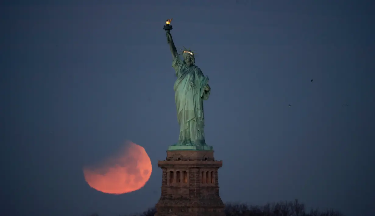 Pemandangan ketika Patung Liberty dihiasi oleh supermoon di Brooklyn, New York, Amerika Serikat, Rabu (31/1). Namun demikian, hanya sebagian gerhana yang terlihat di Pantai Timur Amerika. (AP Photo/Julio Cortez)