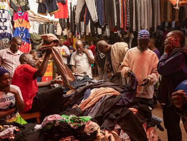 Pembeli memilih barang dari tumpukan pakaian bekas yang dijual di pasar di Kampala pada 7 Oktober 2023. (BADRU KATUMBA / AFP)