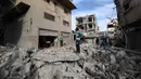 Anak-anak Palestina berjalan di tengah reruntuhan bangunan yang hancur akibat serangan Israel di kamp pengungsi Bureij di Jalur Gaza bagian tengah pada 27 April 2025. (Eyad BABA/AFP)