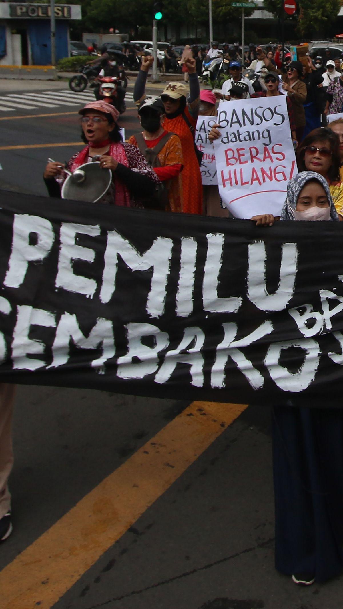 Emak-emak membentangkan spanduk hitam bertuliskan 'Pemilu banjir bansos, sembako jadi mahal'.&nbsp;Merdeka.com/Arie Basuki&nbsp;