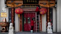 Seorang pekerja yang mengenakan masker membersihkan lentera berdebu di luar restoran di distrik perbelanjaan Wangfujing, Beijing, China, Rabu (14/12/2022). Mulai hari ini, Komisi Kesehatan Nasional China melaporkan penurunan kasus harian COVID-19 sejak pemerintah melonggarkan pengujian PCR setelah kasus harian mencapai rekor tertinggi. (AP Photo/Andy Wong)
