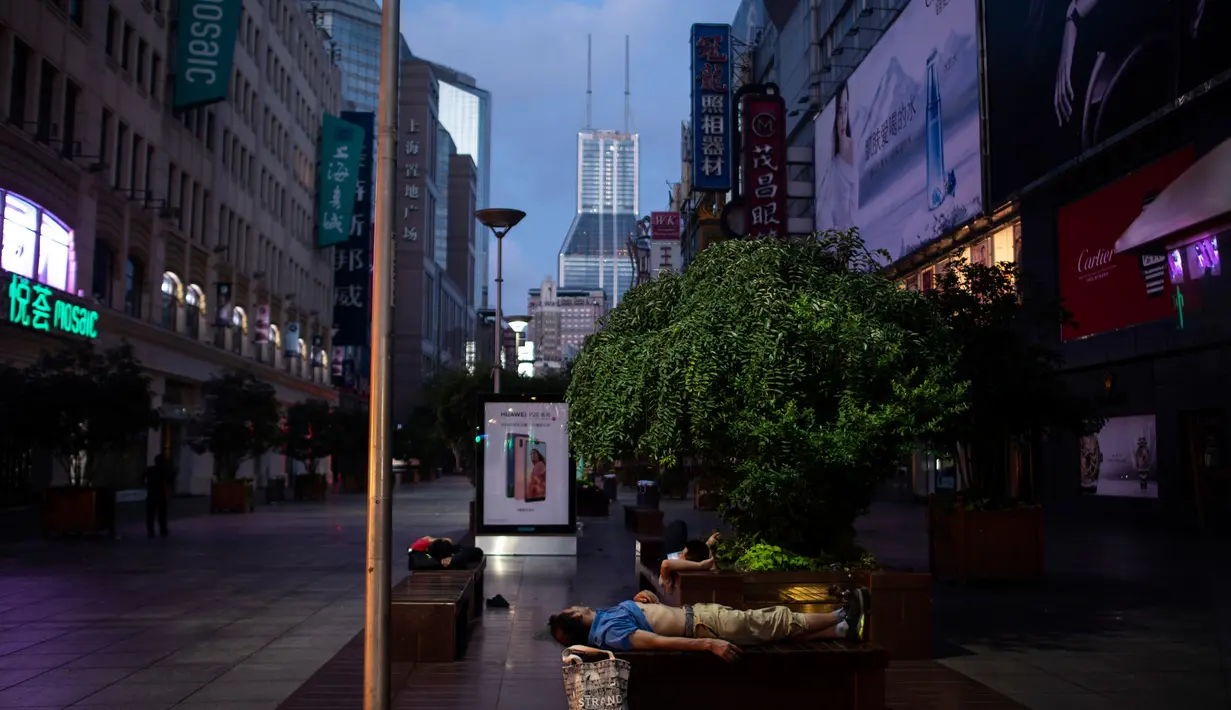 Sejumlah orang tidur bangku di sepanjang Nanjing East Road, Shanghai (8/8). Penduduk setempat mencari cara untuk menjaga tagihan listrik yang meroket selama musim panas. (AFP Photo/Johannes Eisele)