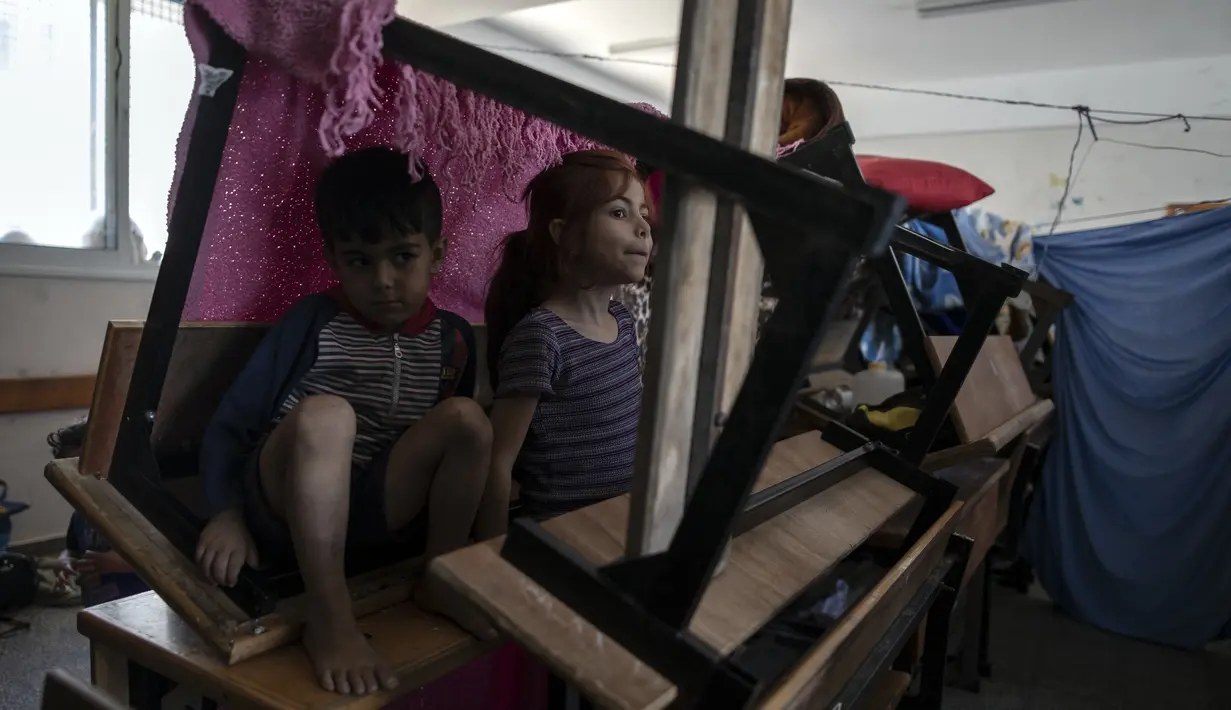 Dua orang anak berlindung di sekolah setelah melarikan diri dari serangan rudal hebat Israel di pinggiran Kota Gaza, Rabu (19/5/2021). Warga Gaza mengungsi dengan kondisi yang memprihatinkan karena terbatasnya layanan kesehatan, listrik, persediaan makanan dan air bersih. (AP Photo/Khalil Hamra)