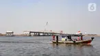 Kapal tradisional melintas dekat proyek pembangunan jembatan penghubung Dadap Tangerang-Pulau C di Kamal Muara, Penjaringan, Jakarta Utara, Minggu (17/11/2019). Jembatan tersebut nantinya akan menghubungkan wilayah Dadap di Tangerang dengan reklamasi Pulau C di Jakarta. (merdeka.com/Iqbal Nugroho)