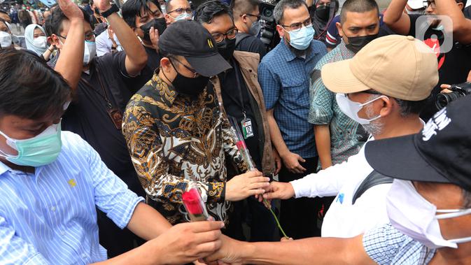 Mantan wakil ketua KPK Bambang Widjojanto memberikan bunga ke Novel Baswedan di luar Gedung KPK, Jakarta, Kamis (30/9/2021). 57 + 1 pegawai KPK yang tak lolos TWK untuk alih status ASN diberhentikan dengan hormat per 30 September 2021. (/Herman Zakharia)