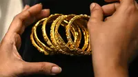 Gambar diambil pada 11 Agustus 2021 menunjukkan seorang pelanggan memegang gelang emas di sebuah toko perhiasan di Mumbai, India. Putus asa mendapatkan uang tunai, banyak keluarga dan usaha kecil menjual perhiasan emas sebagai jaminan untuk mendapatkan pinjaman jangka pendek. (Punit PARANJPE/AFP)