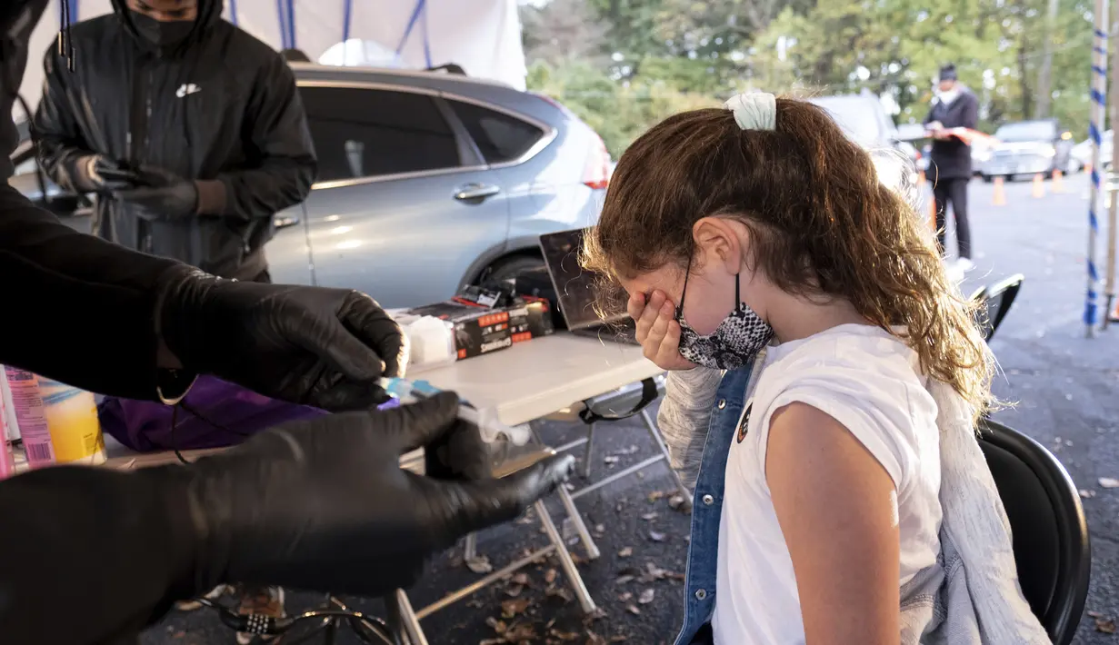 Leah Lefkove (9) menutupi wajahnya saat menunggu ayahnya Dr. Ben Lefkove memberinya vaksin COVID-19 pada hari pertama vaksinasi anak 5 - 11 tahun di Decatur, Georgia, Rabu (3/11/2021). Ini menjadi langkah perdana vaksinasi Covid-19 bagi anak kecil di Amerika Serikat. (AP Photo/Ben Gray)