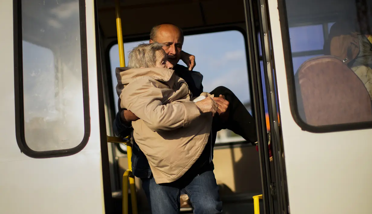 <p>Seorang perempuan dibawa keluar dari bus dengan orang-orang yang melarikan diri dari Mariupol, Tokmak dan Berdyansk saat mereka tiba di pusat penerimaan pengungsi di Zaporizhzhia, Ukraina, Selasa(3/5/2022). Ribuan warga Ukraina terus meninggalkan wilayah yang diduduki Rusia. (AP Photo/Francisco Seco)</p>