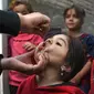 Tenaga kesehatan (kiri) memberikan vaksin polio kepada seorang anak selama kampanye vaksinasi di kawasan tua Kabul, Afghanistan pada 8 November 2021. Vaksinasi tersebut merupakan yang pertama sejak Taliban berkuasa di Afghanistan. (WAKIL KOHSAR / AFP)