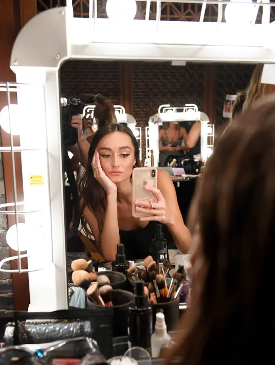 Model berselfie di belakang panggung sebelum tampil mengenakan The Australian Collection Show 2019 selama Miami Swim Week di Miami Beach, Florida (14/7/2019). Miami Swim Week menampilkan pakaian renang yang berlangsung 11 - 16 Juli 2019. (AFP Photo/Jason Koerner)