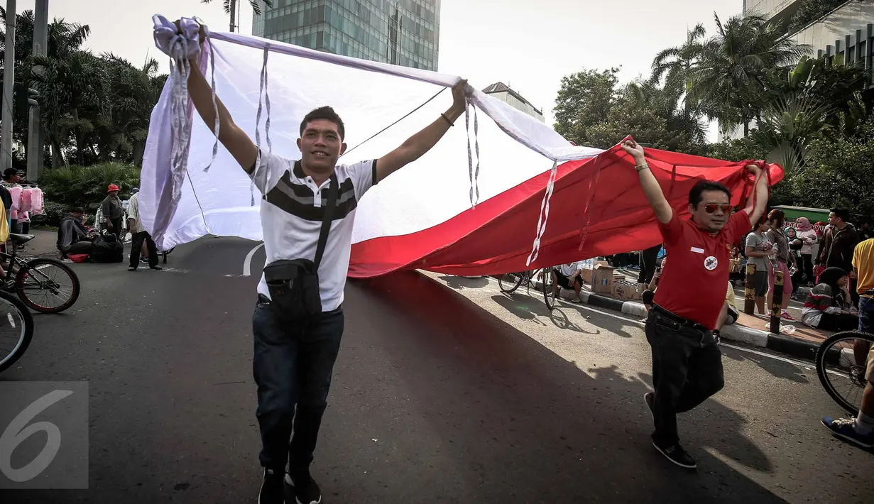 Peserta membentangkan bendera merah putih raksasa pada Karnaval Cinta Budaya NKRI di MH Thamrin, Jakarta, Minggu (20/11). Karnaval ini bertujuan merawat dan menyiram perdamaian, toleransi, harmoni dan persaudaraan kebangsaan. (Liputan6.com/Faizal Fanani)