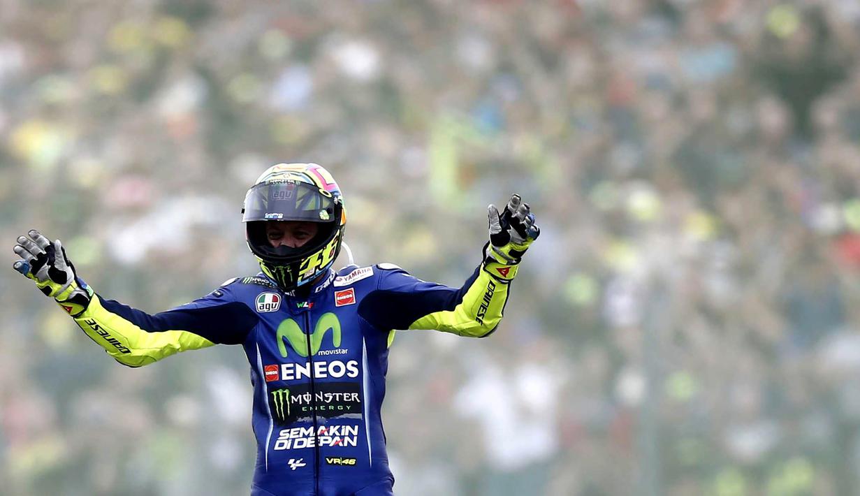 Pebalap Movistar Yamaha, Valentino Rossi, mengangkat tangan saat finish pertama pada MotoGP Belanda di Sirkuit Assen, Assen, Minggu (25/6/2017). Riders asal Italia itu memiliki catatan waktu 41 menit 41,149 detik. (AFP/Vincent Jannink) 