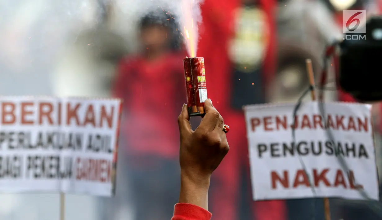 Buruh menyalakan bom asap saat menutup aksi Hari Buruh Internasional di Jalan Medan Merdeka Barat, Jakarta, Rabu (5/1/2019). Buruh dari berbagai organisasi merayakan Hari Buruh Internasional di Kawasan Silang Barat Daya Monas. (Liputan6.com/Helmi Fithriansyah)
