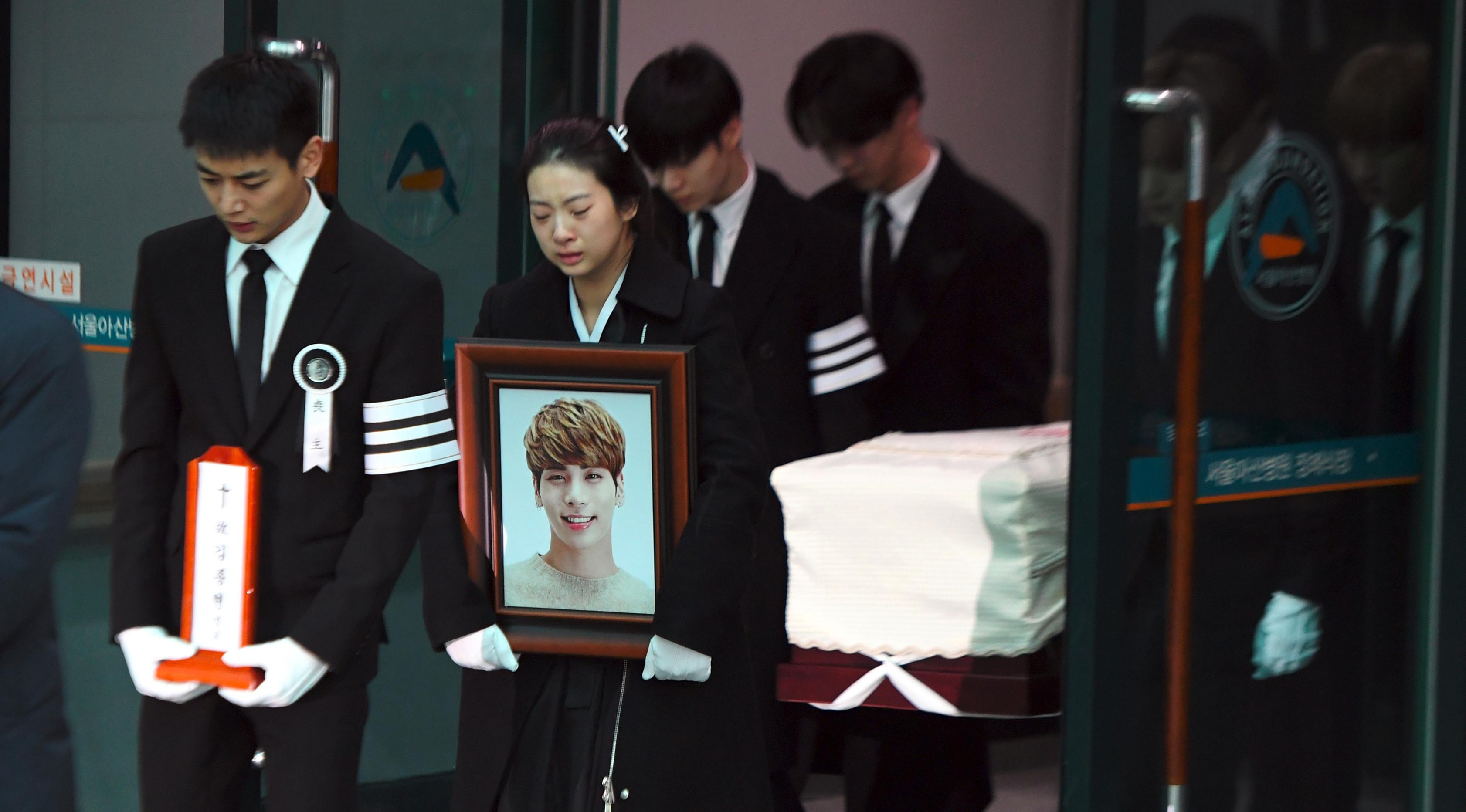 Minho (kiri) membawa plakat pada prosesi pelepasan jenazah Jonghyun SHINee menuju tempat pemakaman dari Asan Hospital, Seoul, Kamis (21/12). Minho berusaha tegar saat memimpin iringan bersama kakak Jonghyun yang membawa foto sang adik. (JUNG Yeon-Je/AFP)