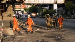 Pakar penyelamat Kamboja dan Thailand berjalan melalui reruntuhan bangunan untuk operasi pencarian di lokasi kebakaran besar kasino hotel Kamboja di Poipet, Kamboja, Jumat (30/12/2022). Pihak berwenang Thailand mengatakan bahwa lebih dari 50 orang dirawat di rumah sakit di Sa Kaeo, di mana 13 di antaranya menggunakan alat bantu hidup atau life support. (AP Photo/Heng Sinith)