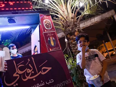 Anak laki-laki makan popcorn selama bulan suci Ramadan di Bilad al-Qadeem, ibukota Bahrain, Manama, di tengah pandemi COVID-19 yang sedang berlangsung (10/5/2020). (AFP/Mazen Mahdi)