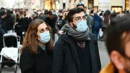 Orang-orang memakai masker di sepanjang jalan perbelanjaan mewah Via Condotti di pusat kota Roma, Italia, Minggu (5/12/2021). Kota Roma memberlakukan kewajiban penggunaan masker di ruang terbuka pusat kota dan area perbelanjaan sibuk lainnya hingga 31 Desember mendatang. (Vincenzo PINTO/AFP)