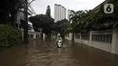 Pengendara motor melintasi banjir di Jalan Hang Lekir, Kebayoran Lama, Jakarta Selatan, Rabu (1/1/2020). Banjir tersebut disebabkan karena tingginya intensitas hujan yang mengguyur sejak Selasa (31/12/2019). (Liputan6.com/Johan Tallo)