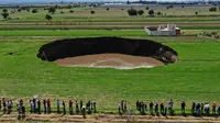 Pemandangan udara dari sinkhole yang ditemukan oleh petani di lahan pertanian di Santa Maria Zacatepec, negara bagian Puebla, Meksiko pada 30 Mei 2021. Lubang yang penuh dengan air itu pada hari Minggu lebarnya hanya sekitar 30 meter. (JOSE CASTAÑARES/AFP)