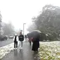 Orang-orang berjalan di sepanjang jalan selama hujan salju pertama musim ini di Katoomba di pegunungan Blue Mountains (10/6/2021). Suasana udara yang sejuk dan bersalju di Blue Mountains ketika musim dingin menjadi daya tarik wisatawan lokal di Sydney. (AFP/Saeed KHAN)