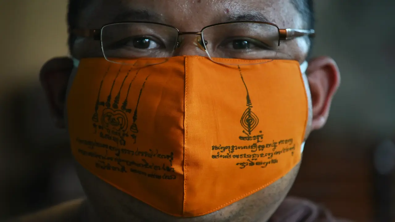 Biksu Budddha Chamnanwej Sutthiyano mengenakan masker terbuat dari botol plastik daur ulang dan ditulisi mantra spiritual, (Lillian Suwanrumpha/AFP)