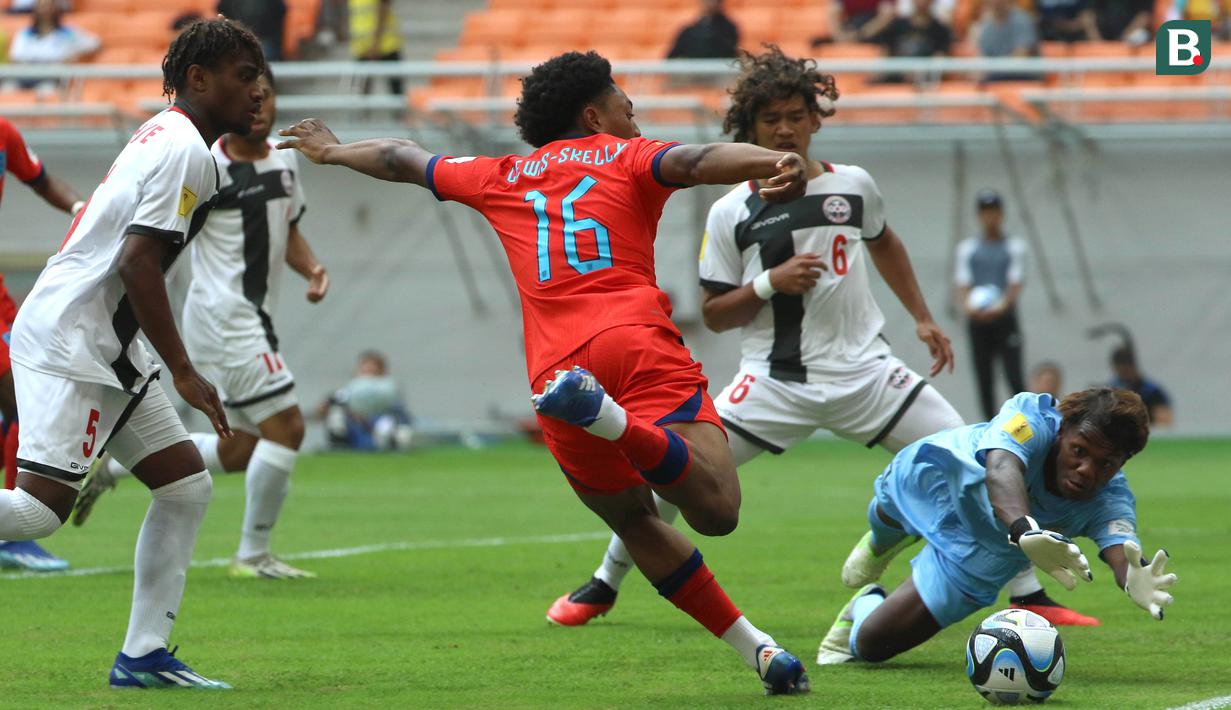 Kiper Timnas Kaledonia Baru U-17, Nicolas Kutran (kanan) berusaha menghalau bola tendangan dari pemain Timnas Inggris U-17, Myles Lewis-Skelly (tengah) dalam pertandingan Grup C Piala Dunia U-17 2023 yang berlangsung di Jakarta International Stadium, Sabtu (11/11/2023). (Bola.com/Ikhwan Yanuar)