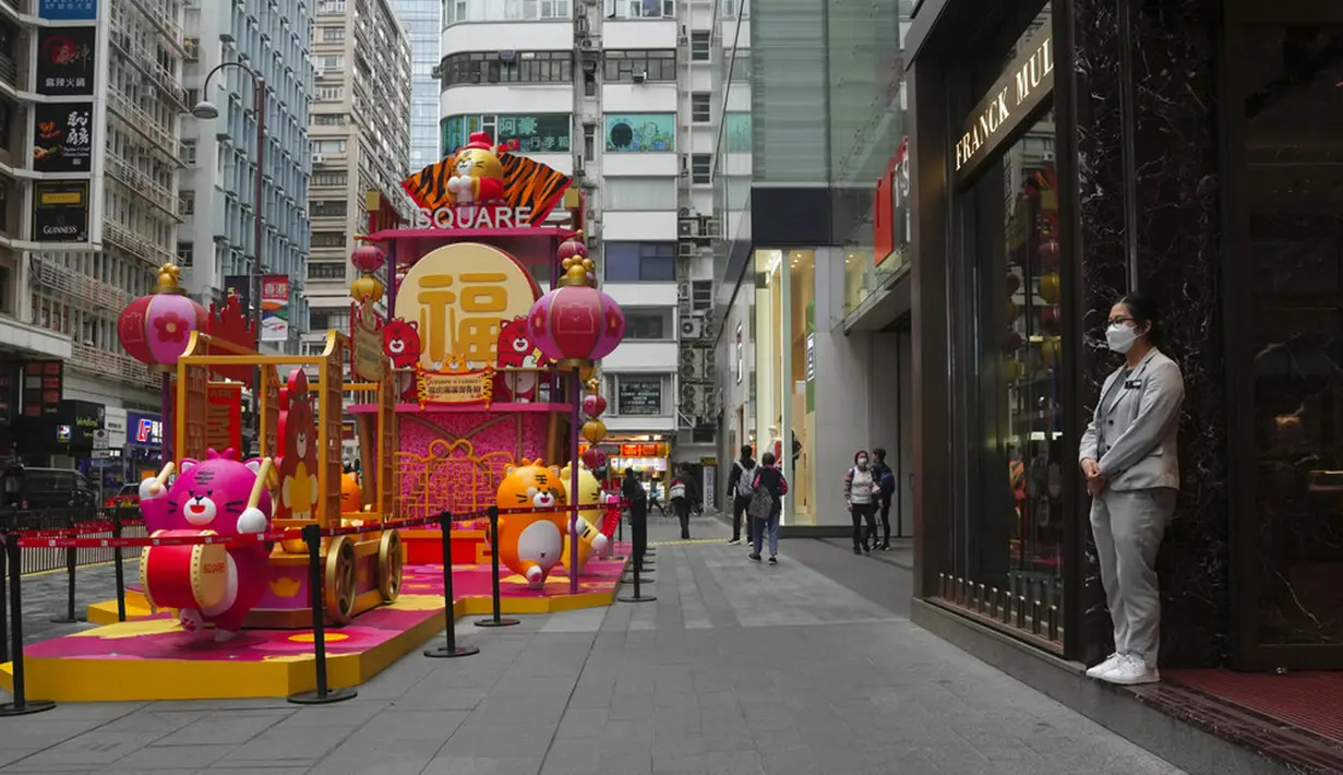 Seorang asisten toko yang mengenakan masker menunggu pelanggan di sebuah toko di Hong Kong, Jumat (28/1/2022). Hong Kong memangkas masa karantina wajib bagi orang-orang yang datang dari luar negeri dari 21 menjadi 14 hari. (AP Photo/Kin Cheung)