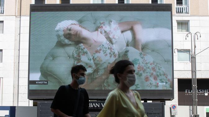Pejalan kaki melewati layar yang menunjukkan model Vivetta selama Milan Digital Fashion Week, di Milan, Italia pada 14 Juli 2020. Empat puluh rumah mode menampilkan koleksi pakaian untuk musim semi/musim panas 2020 dalam format digital di tengah pandemi Covid-19. (AP Photo/Luca Bruno)
