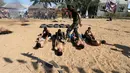 Seorang militan berjalan tubuh anak Palestina selama latihan militer di sebuah kamp musim panas yang diselenggarakan oleh Islamic Jihad Movement di Khan Younis di Jalur Gaza selatan (13/7). (REUTERS/Ibraheem Abu Mustafa)