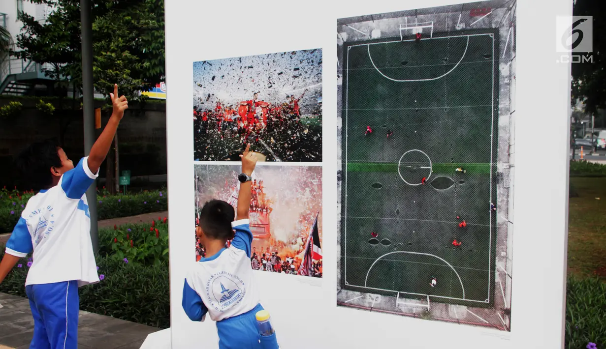 Siswa SD Negeri Menteng 01 mengamati karya foto yang dipamerkan dalam pameran fotografi Rekam Jakarta di Taman Menteng, Kamis (29/8/2019). Kegiatan tersebut dalam rangka edukasi bagi siswa mengenal profesi foto jurnalistik. (Liputan6.com/Marsha Aulia)