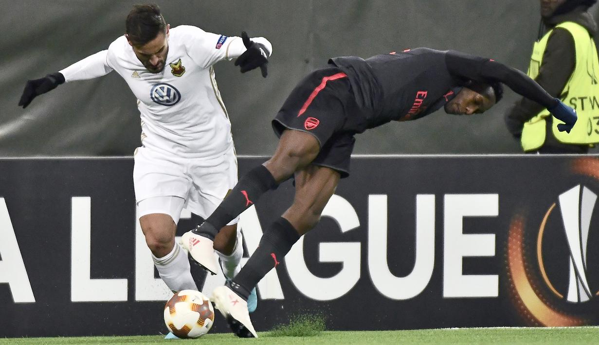 Pemain Ostersund, Sotirios Papagiannopoulos (kiri) berebut bola dengan pemain Arsenal, Danny Welbeck pada babak 32 besar Liga Europa di Jamtkraft Arena, Ostersund, Swedia (15/2/2018). Arsenal menang 3-0. (Robert Henriksson/TT News Agency via AP)