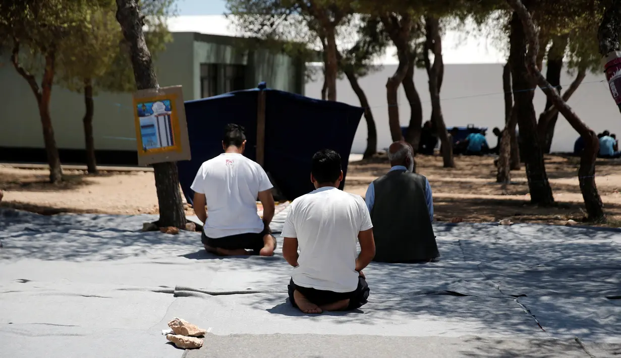 Sejumlah imigran melaksanakan salat pada hari pertama bulan Ramadan, di kamp pengungsian milik pemerintah Yunani di Schisto, Athena, Senin (6/6). Para imigran itu membuat masjid darurat di sebuah halaman terbuka. (REUTERS/Alkis Konstantinidis)
