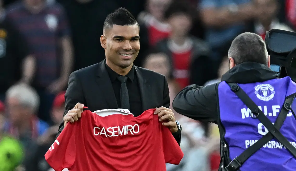 Gelandang Manchester United Casemiro berpose dengan jersenya saat diperkenalkan kepada para pendukung sesaat sebelum laga MU vs Liverpool dimulai di stadion Old Trafford, Senin (22/8/2022). Casemiro secara resmi akan mengakhiri masa sembilan tahun yang sangat sukses di Real Madrid dengan 18 trofi, termasuk lima Liga Champions. (Paul ELLIS / AFP)