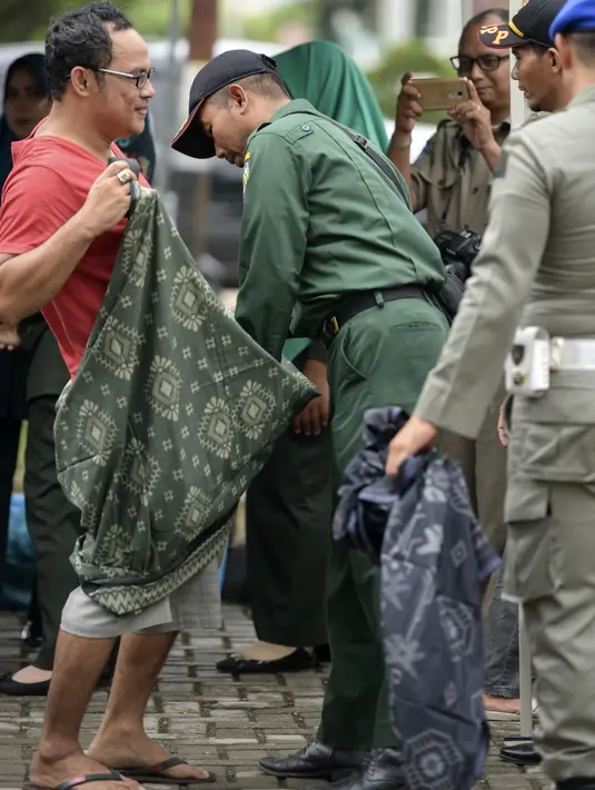 Polisi Syariat Islam memakaikan kain sarung pada warga bercelana pendek saat razia penertiban hukum syariat islam di Banda Aceh, Aceh, Selasa (19/9). Selain diberikan sarung, mereka dibina supaya berpakaian sesuai dengan peraturan (CHAIDEER MAHYUDDIN/AFP)