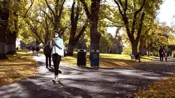 Seorang wanita berjalan sambil bermain ponsel di taman kota di Melbourne, Australia (3/6/2021). Pihak berwenang mengumumkan Lockdown di Melbourne diperpanjang tujuh hari lagi ketika negara itu berusaha untuk membasmi sekelompok kasus Covid-19 di Melbourne. (AFP Photo/William West)