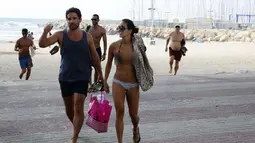 Militer Israel mengingatkan pengunjung pantai untuk berlindung karena militan Palestina diduga akan melancarkan roket balasan ke sekitar pantai, Israel, Senin (14/07/2014) (AFP PHOTO/GALI TIBBON)