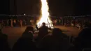Para penari melakukan ritual kuno di sekitar api unggun mengusir roh-roh jahat di jalan-jalan Batanovci, Bulgaria, Kamis (13/1/2022). Untuk dua tahun ini festival topeng memiliki arti ekstra: orang-orang berharap itu akan membawa kelegaan dari kesengsaraan pandemi corona. (AP/Valentina Petrova)