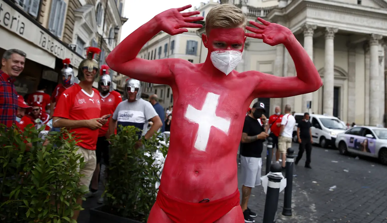 Suporter Swiss yang tubuhnya dicat dengan warna bendera Swiss berjalan di pusat kota Roma menjelang laga Grup A Euro 2020 antara Italia dan Swiss, Rabu (16/6/2021). Dalam laga tersebut, Timnas Italia menghajar Swiss dengan skor 3-0. (Cecilia Fabiano/LaPresse via AP)