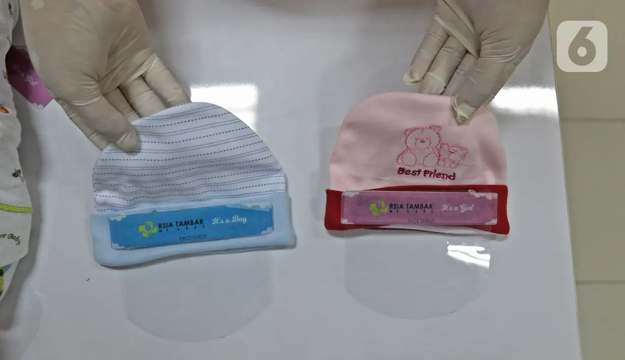 Perawat kamar bayi menunjukkan face shield (italic) di  RSIA Tambak, Jakarta, Selasa (14/4/2020). RSIA Tambak membuat face shield (italic) mandiri menggunakan plastik mika, direkatkan dengan karet atau bandana menggunakan topi bayi menghindarkan alergi pada kulit bayi. (Liputan6.com/Herman Zakharia)