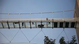Sejumlah orang melintasi jembatan kaca di Shijiazhuang, Provinsi Hebei, China, Sabtu (24/11). Jembatan ini memiliki panjang 100 meter. (AFP)