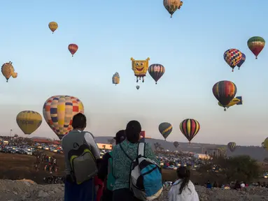 Warga melihat balon udara yang menghiasi langit di Cajititlan, Meksiko, Minggu (7/5).  Festival balon udara ini menjadi tontonan menarik bagi warga sekitar dan wisatawan. (AFP PHOTO / Hector Guerrero)