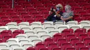Dua orang penonton saat menyaksikan pertandingan antara  VfB Stuttgart melawan SC Freiburg pada laga Bundesliga, Sabtu (19/9/2020). Sejumlah liga di Eropa telah mengijinkan fans menonton langsung pertandingan di stadion. (AP Photo/Matthias Schrader)