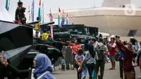 Warga berfoto di atas kendaraan milik TNI saat pameran alat utama senjata (alutsista) di Lapangan Monumen Nasional (Monas) Jakarta, Minggu (24/9/2023). (Liputan6.com/Faizal Fanani)