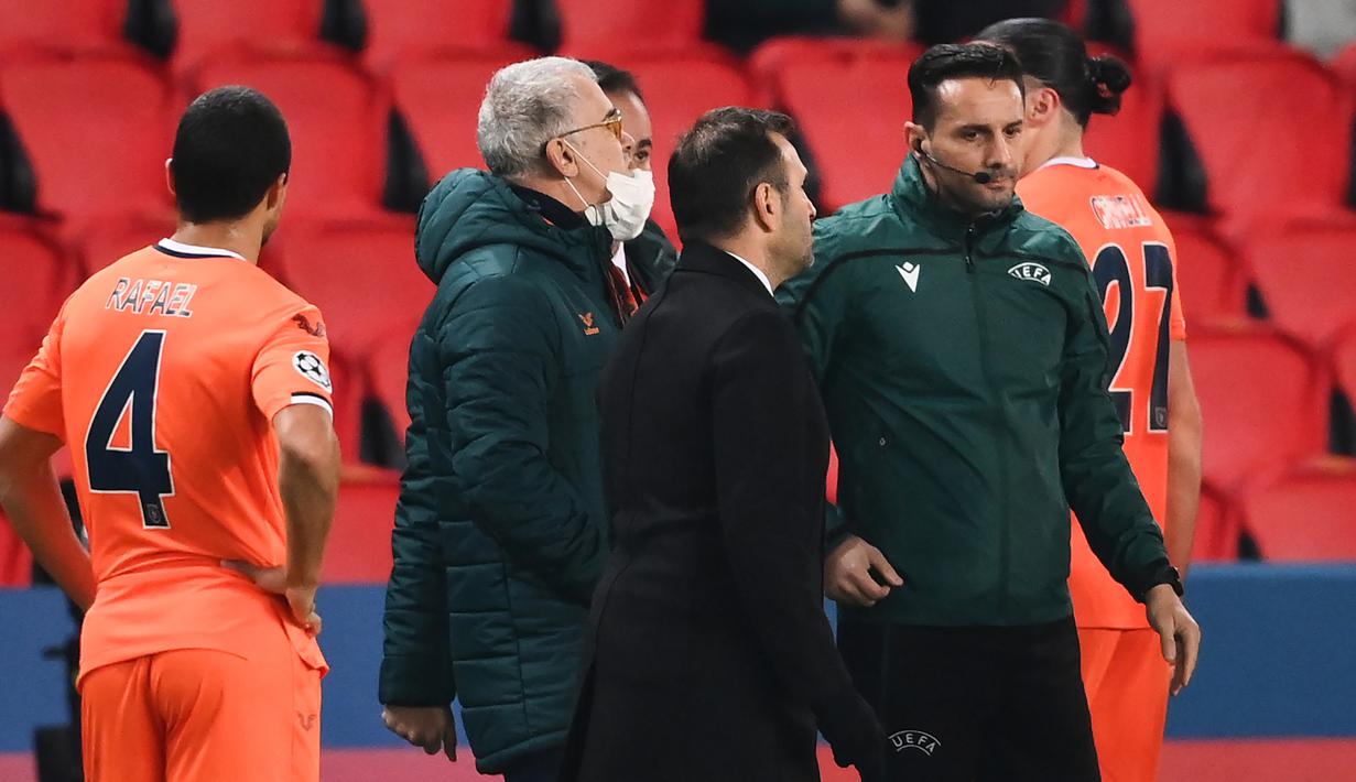 Pelatih Istanbul Basaksehir, Okan Buruk (kedua dari kanan), berbicara dengan asisten wasit ke-4, Sebastian Coltescu usai dihentikannya laga lanjutan Liga Champions Grup H melawan Paris Saint-Germain di Parc des Princes Stadium, Selasa (8/12/2020). (AFP/Franck Fife)