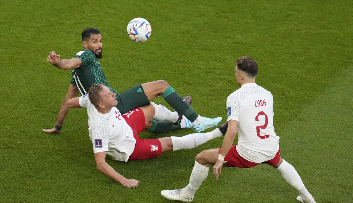 Penyerang Arab Saudi, Saleh Al-Shehri berebut bola dengan dua pemain Polandia, Kamil Glik dan Matty Cash selama pertandingan grup C Piala Dunia 2022 Qatar di Education City Stadium di Al Rayyan, Qatar, Sabtu (26/11/2022). Kemenangan membuat Polandia kini memimpin Grup C Piala Dunia 2022. Lewandowski dkk kini mengoleksi 4 poin. (AP Photo/Francisco Seco)