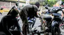 Montir membersihkan sepeda motor konsumen usai terendam banjir di kawasan Mampang, Jakarta, Minggu (21/2/2021). Banjir yang melanda Ibu Kota Jakarta pada Sabtu (20/2) menyebabkan banyak kendaraan warga mengalami kerusakan akibat terendam air. (Liputan6.com/Faizal Fanani)