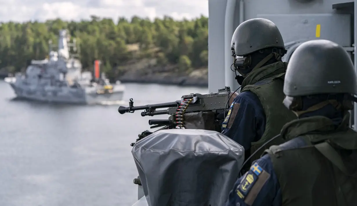 Kapal penyapu ranjau HMS Ulvön (kiri) memindai perairan untuk mencari ranjau saat penembak mesin di kapal HMS Trosso (A264) mencari ancaman selama latihan ranjau di luar Vastervik, Swedia, 21 September 2021. (JOHAN NILSSON/TT NEWS AGENCY/AFP)